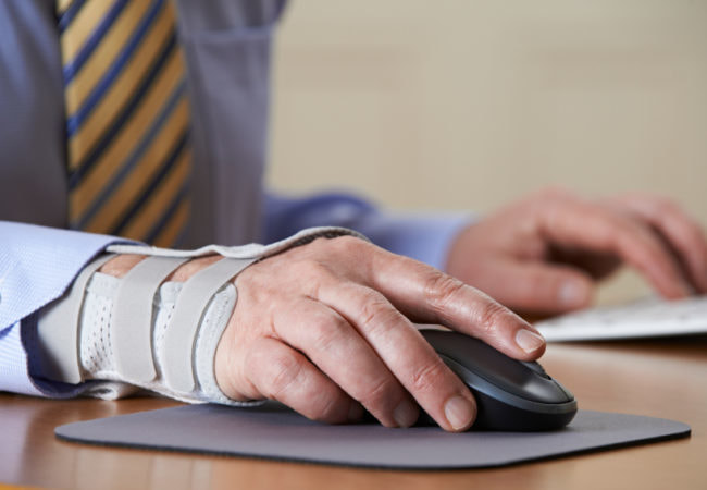 Picture of man at computer with his right hand in a brace