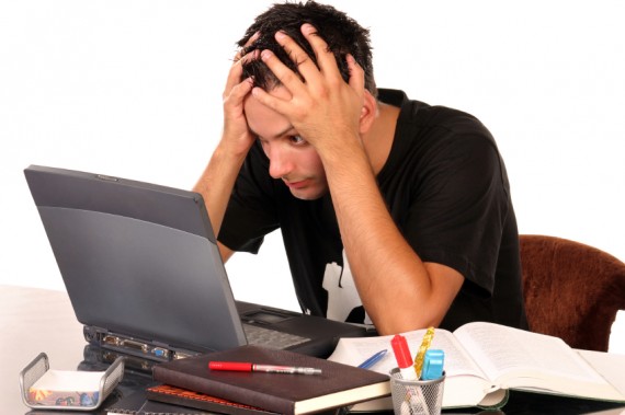Picture of overwhelmed student at desk with computer and books